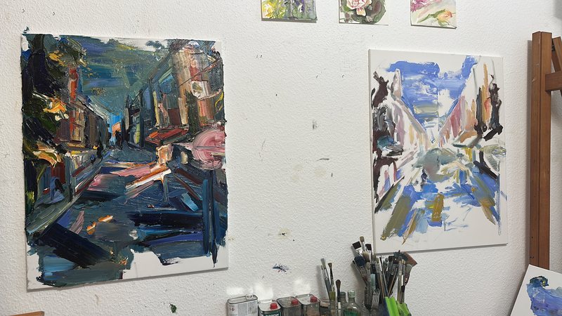 Zwei Straßenstudien in Öl an der Atelierwand, davor Pinsel und Malmittel